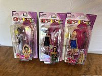 Three vintage Spice Girls dolls in original packaging displayed upright on a light-colored surface.