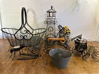 Full lot of vintage metal baskets and decorative metal figurines arranged on a wooden surface against a plain white background.