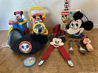 Photo showing a collection of vintage Mickey Mouse items including toys and Disneyland hat arranged on a surface.