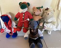Five vintage plush bears placed on a flat surface against a wall, showing front views and details of each bear's outfit and color.
