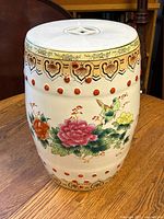 Front view displaying colorful floral and bird motifs with carved circular cutouts and detailed patterned border near top and bottom.