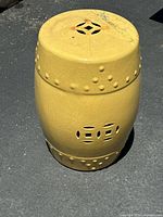 Overall view of the yellow ceramic garden stool showing shape, color, and surface condition.