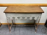 Full front view of side table showing wood top, galvanized steel apron with decorative cutouts, and legs.