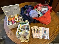 Overview of sewing supplies including yarn, sewing box, and organizer bags on a wooden table.