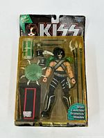 First photo showing a KISS rock star action figure in original blister pack with drum set and weapon accessories.