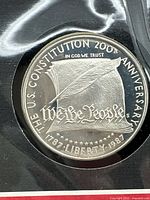 Close-up view of the 1987 silver proof coin commemorating 200th anniversary of U.S. Constitution showing 'We the People' design and inscriptions.