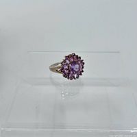 Front view of silver ring with central round amethyst stone surrounded by smaller amethyst stones in a floral arrangement.