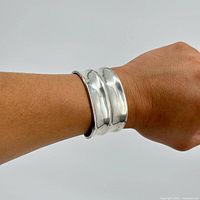 Silver bangle bracelet shown on wrist to indicate size and fit.