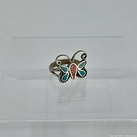 Front view of silver butterfly ring showing turquoise wings and coral body against clear background