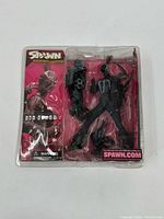 Front view of Spawn Alternate Realities action figure in original blister card packaging with character holding weapon and separate accessory included.