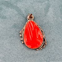 Front view of sterling silver pendant with marbled orange glass on a gray fabric background