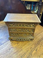Front closed view of the wooden carved jewelry box showing ornate floral carvings and drawer fronts.