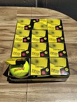 Photo showing all 12 boxed yellow Lightning softballs arranged in two rows of six.