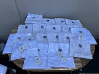 All 19 white football practice jerseys folded and laid out on a flat surface showing quantity and uniform appearance.