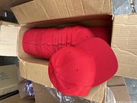 Box containing 21 stacked Richardson solid red baseball caps.
