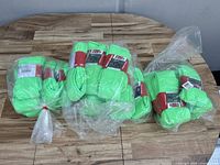 Shows 24 pairs of neon green socks in bundles wrapped in original clear plastic packaging with Pro Feet branding labels, laid out on a wooden surface.