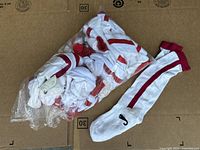 Pack of 24 white socks with red stripes and red cuffs, partially bagged, displayed on cardboard.