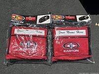 Photo of two red Easton Championship totes in original sealed packaging with personalization area labeled Your Name Here