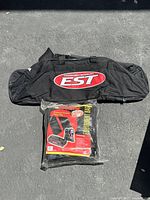 Black duffel bag with EST logo and second Worth equipment bag in packaging on ground.