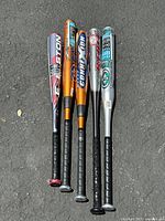 Five aluminum baseball bats laid side by side with branding and grip visible