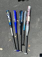 All five aluminum baseball bats lined up flat on the ground showing full length and color details.