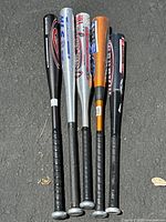 Group of five aluminum baseball bats with black grips, showing different brand logos and colors including black, silver, and orange barrels.