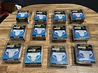 Overview of all thirteen Adams athletic supporters with soft cups in plastic packages arranged on table