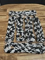 Top view of seven segmented black and white training jump ropes in plastic packaging laid out on a wooden surface.