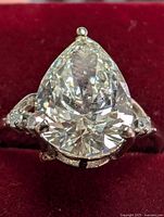 Front-facing view of pear-cut diamond ring resting on red velvet background