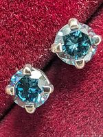 Close-up of both studs on red velvet background, highlighting color and setting