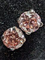 Top-down view of both stud earrings on black surface showing matched pair