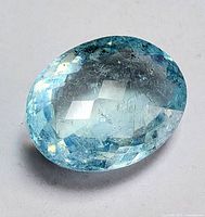 Close-up image of a single oval-shaped, faceted aquamarine gemstone showcasing its light blue color and natural inclusions.