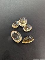 Five faceted citrine gemstones displayed on a black background showing variety of cuts and sizes.