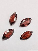 Four loose marquise cut garnet gemstones placed on white background showing size and shape
