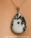 Front view of teardrop-shaped pendant with white and black dendritic gemstone on chain.