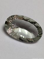 Oval cut genuine green amethyst gemstone with light green hue, showing clear transparency and cut facets.