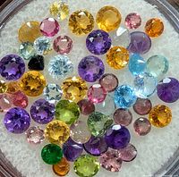 Close-up photo of various colored faceted gemstones in a clear display case.