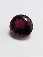 Top-down view showing round faceted shape and deep red color with internal reflections