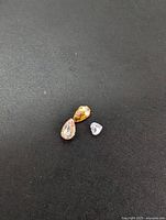 Three natural fancy color diamonds: pear-shaped yellow, pear-shaped light brown, and heart-shaped light purple, displayed on black background.