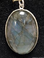 Front view of the oval natural gemstone pendant against black background showing internal structures and color reflections.