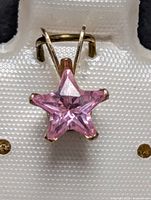 Close-up photo of the pink star-shaped cubic zirconia pendant set in 10k gold.