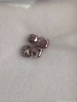 Four loose pink diamonds on white background showing cushion cuts and natural inclusions.