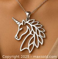 Front view of silver unicorn head pendant worn on a chain, showing detailed cut-out mane and horn.