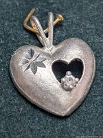 Front view of silver heart-shaped pendant showing the cutout and flower decoration