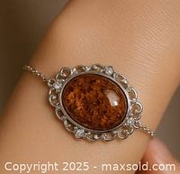 Close-up of amber stone in silver setting on bracelet worn on wrist