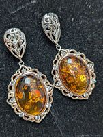 Front view of silver earrings showing amber stones and silver filigree work.