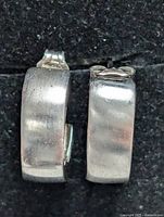 Close-up front view of the silver hoop earrings showing brushed matte texture and shape.