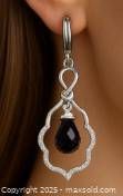 Close-up of earrings worn to show size, shape and style. Shows faceted garnet drop with silver openwork frame.