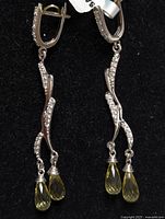 Front view of the pair of silver earrings with lemon quartz teardrop pendants, showing twisted metal design with small clear stones and two lemon quartz dangles per earring.