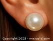 Close-up photo of pearl earring worn in an ear showing size, shape, and color of the pearl.
